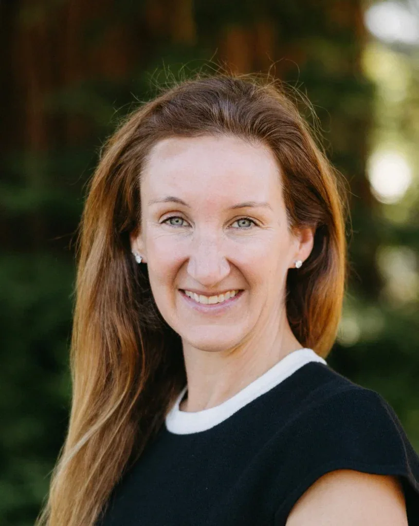 Portrait of Dr. Laura Horsch, Ph.D., smiling outdoors with trees in background.